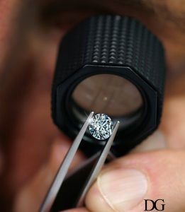 observation d'un diamant à la loupe, tenu par une pince